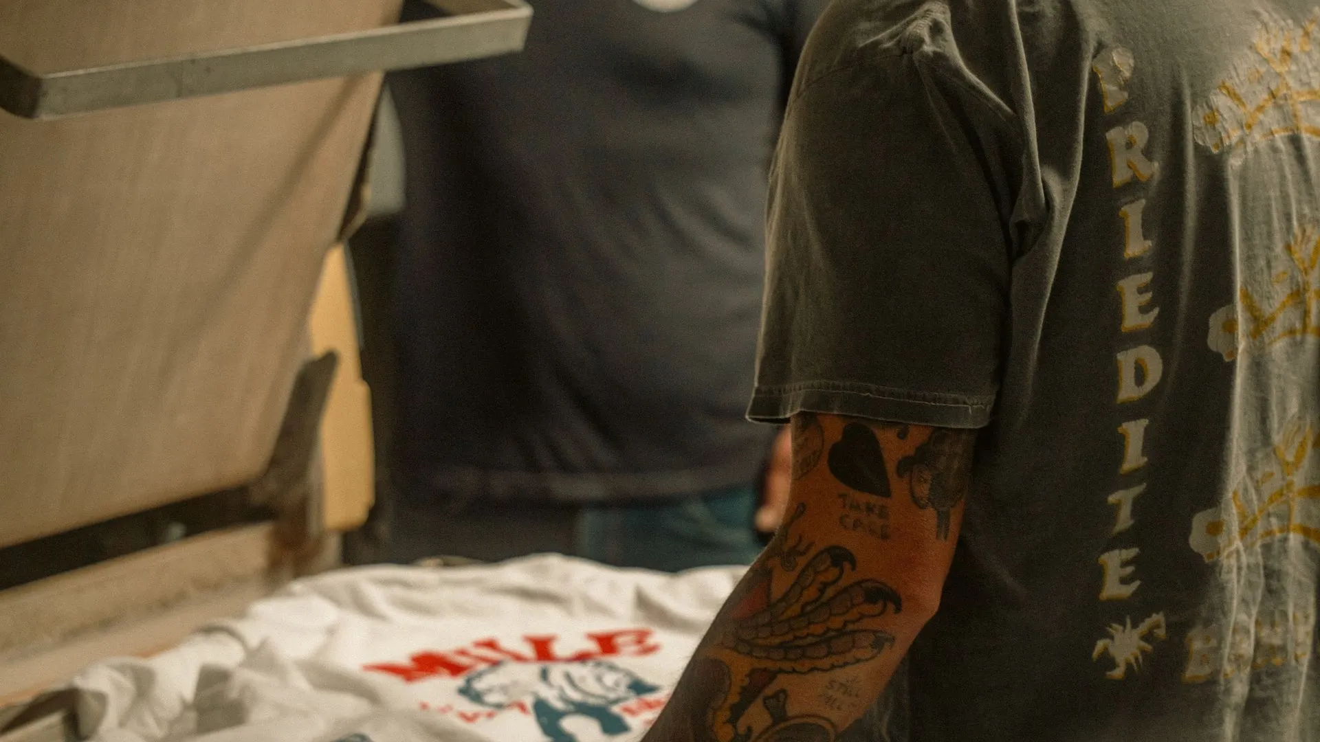 Print shop worker pressing a custom-branded t-shirt in a workshop